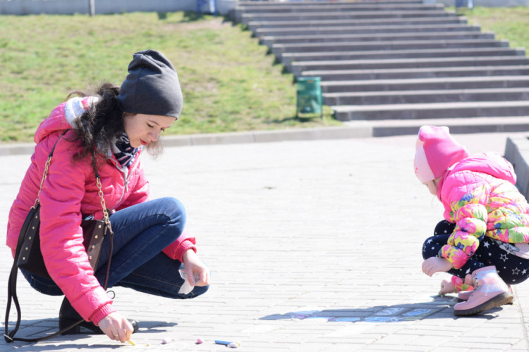 Дети с родителями любят гулять парка и рисовать мелом на асфальте